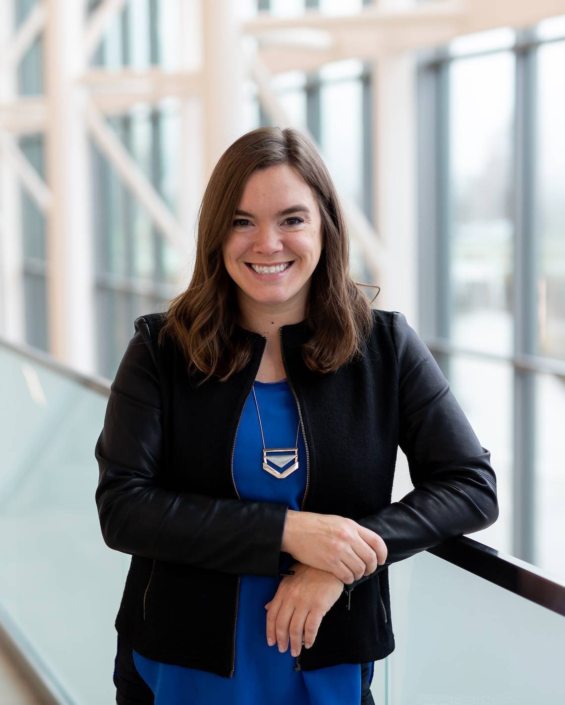 Picture of a person in a blue shirt and black blazer smiling at the camera.